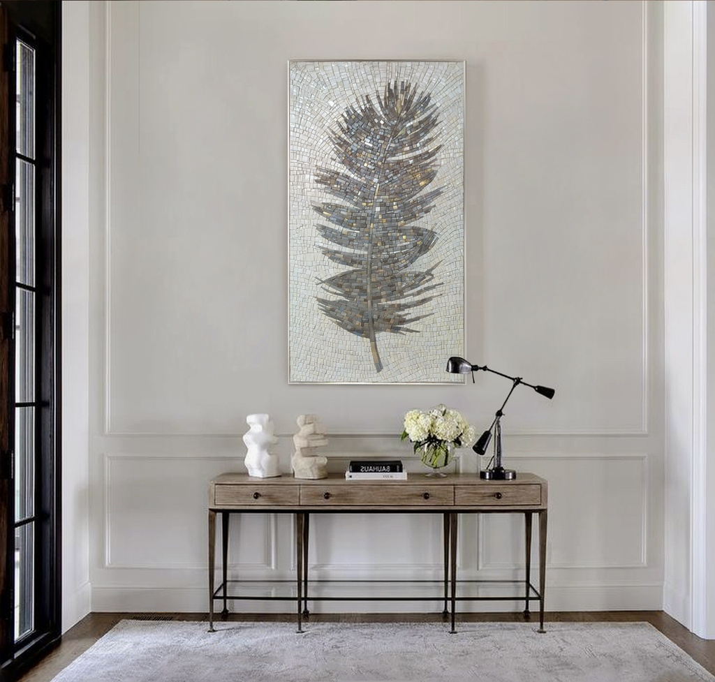 Vertical mosaic wall art featuring a stylized dark grey feather with silver and gold details on a pale icy background